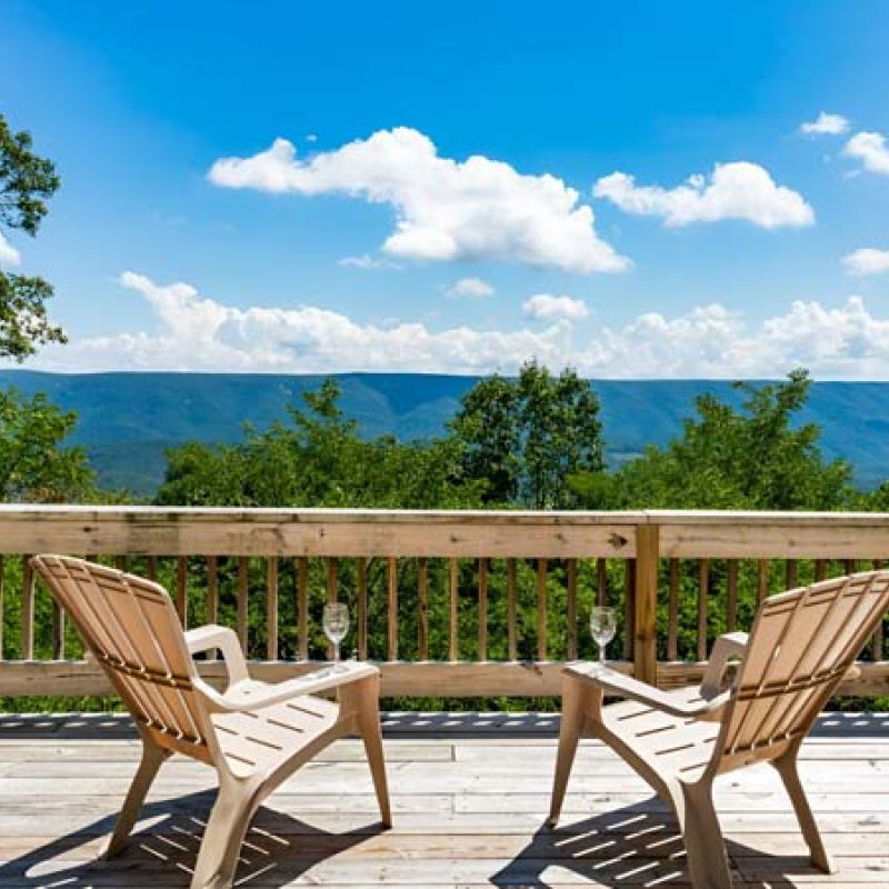 a wooden deck with two chairs overlooking a stunning view