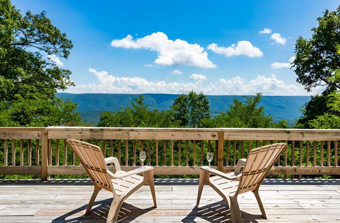 a wooden deck with two chairs overlooking a stunning view