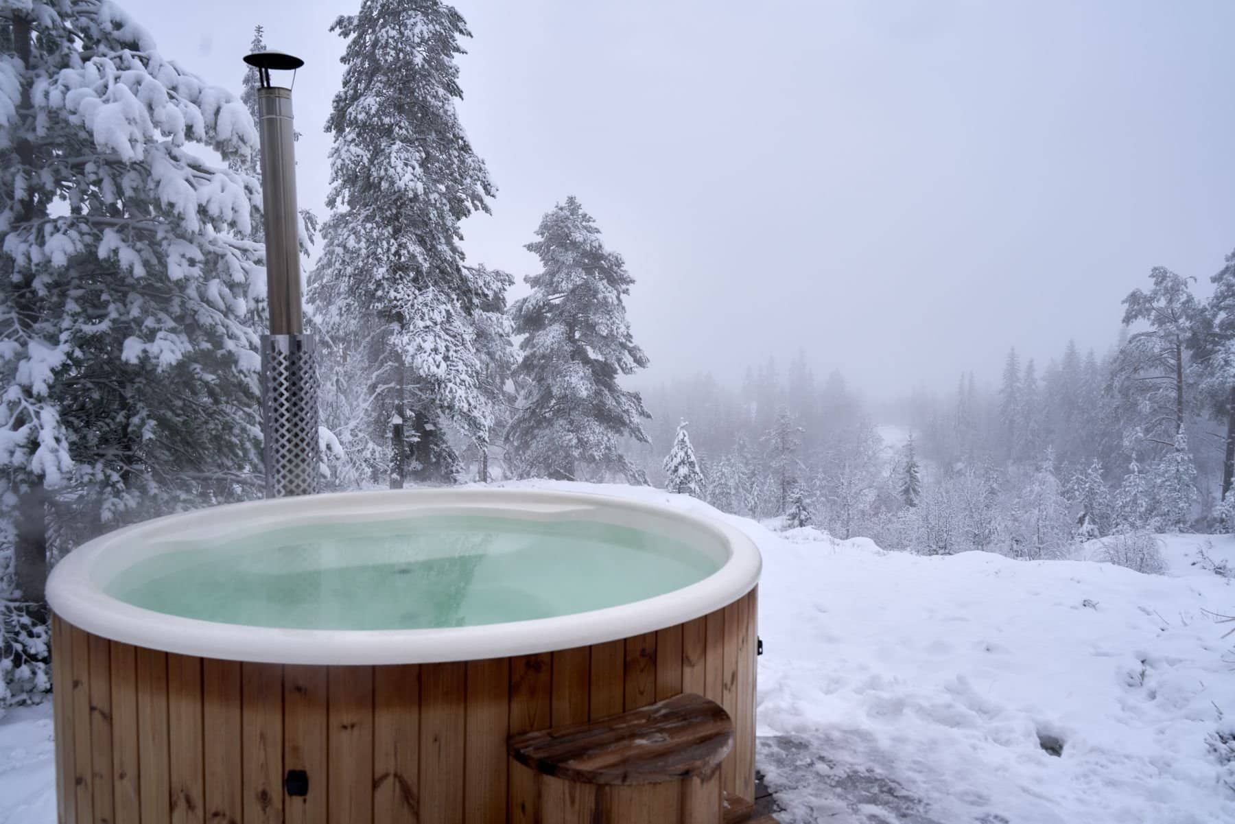 Steaming hot tub on a cabin deck in a snowy forest