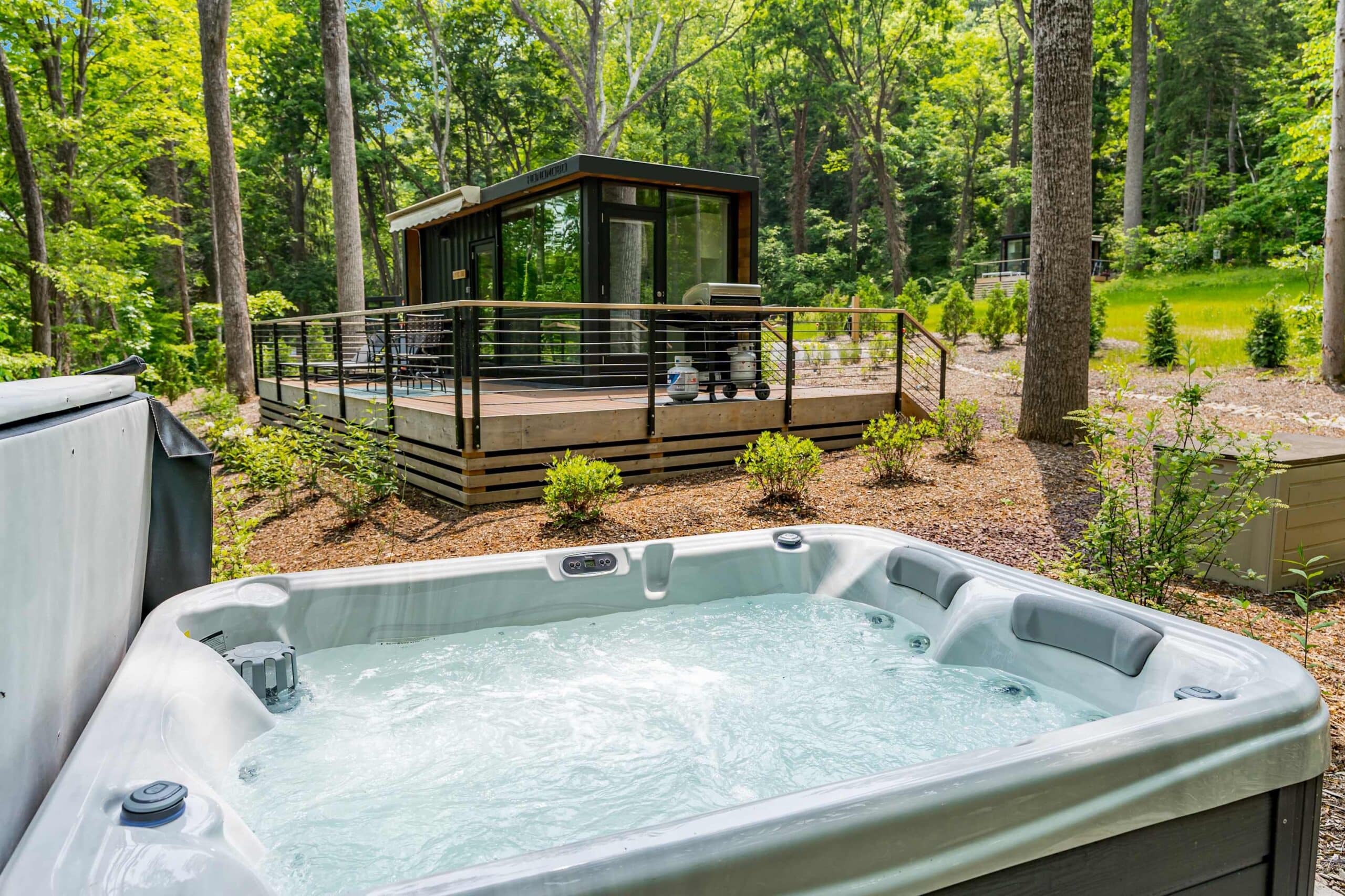 Private hot tub surrounded by forest outside a modern cabin