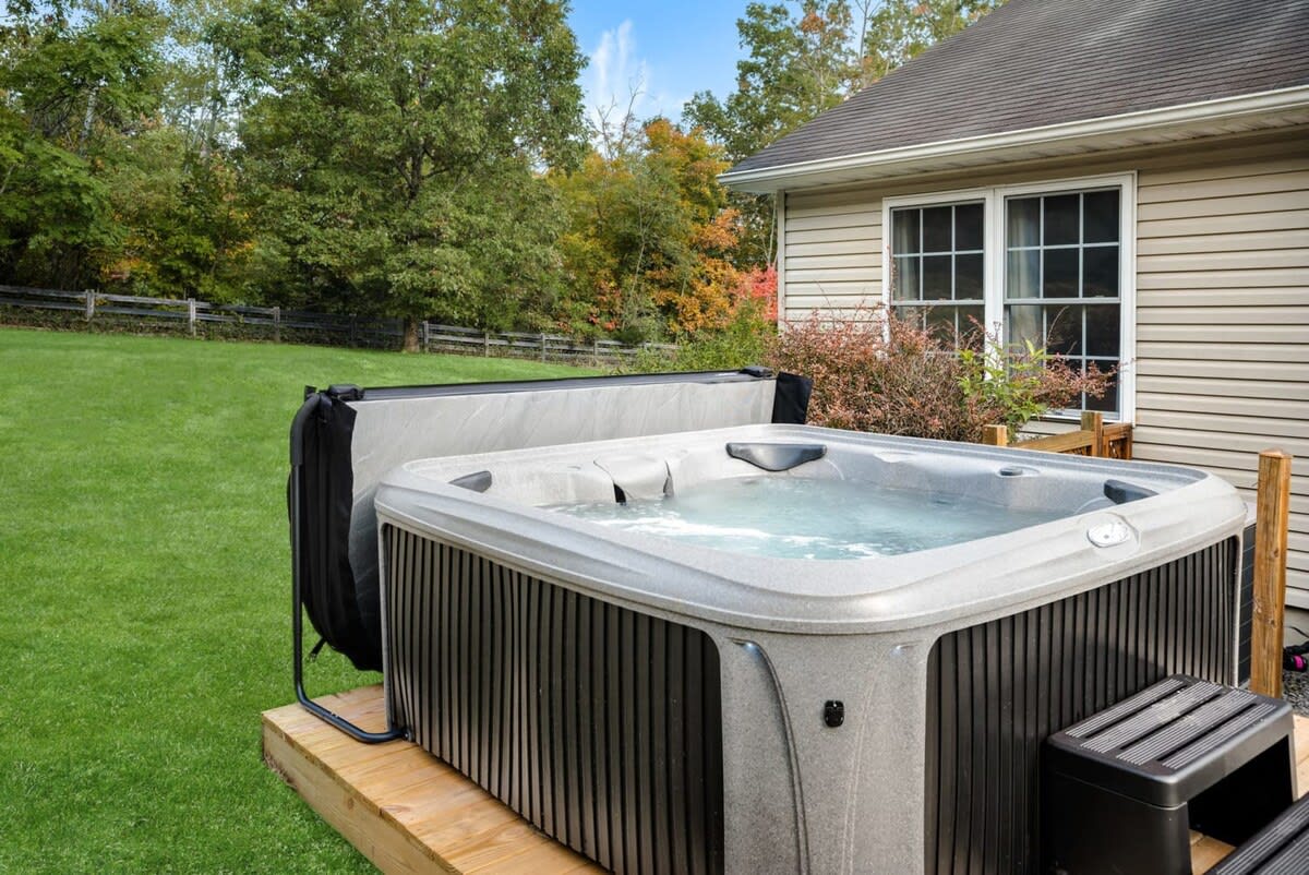 Private hot tub in a backyard with autumn trees behind it